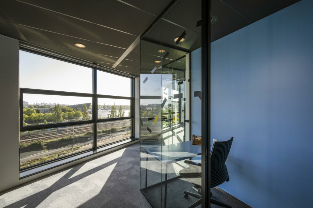 Modern kantoor met glazen vergaderruimte aan de Piet Heinkade met uitzicht op spoorlijnen en het water.